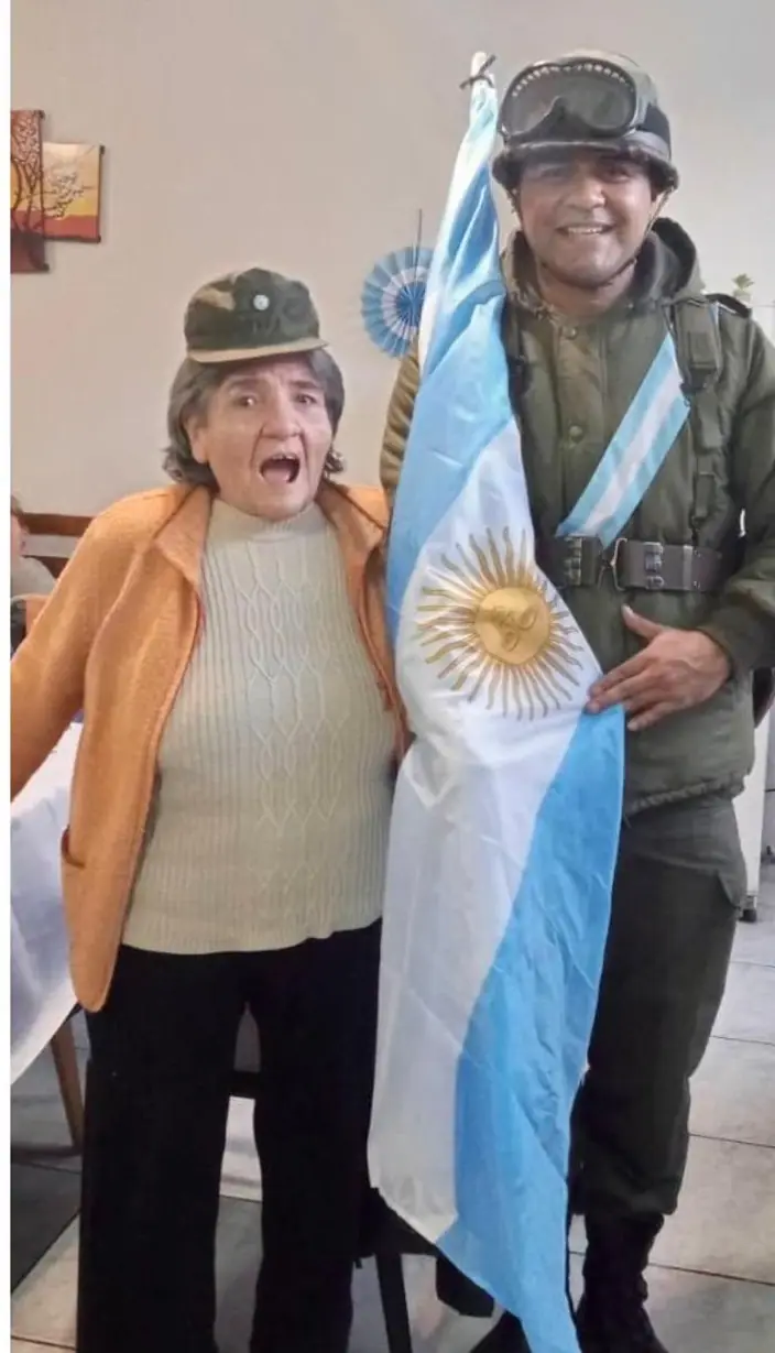 Residente posando con un granadero y la bandera argentina durante un acto patrio en la residencia