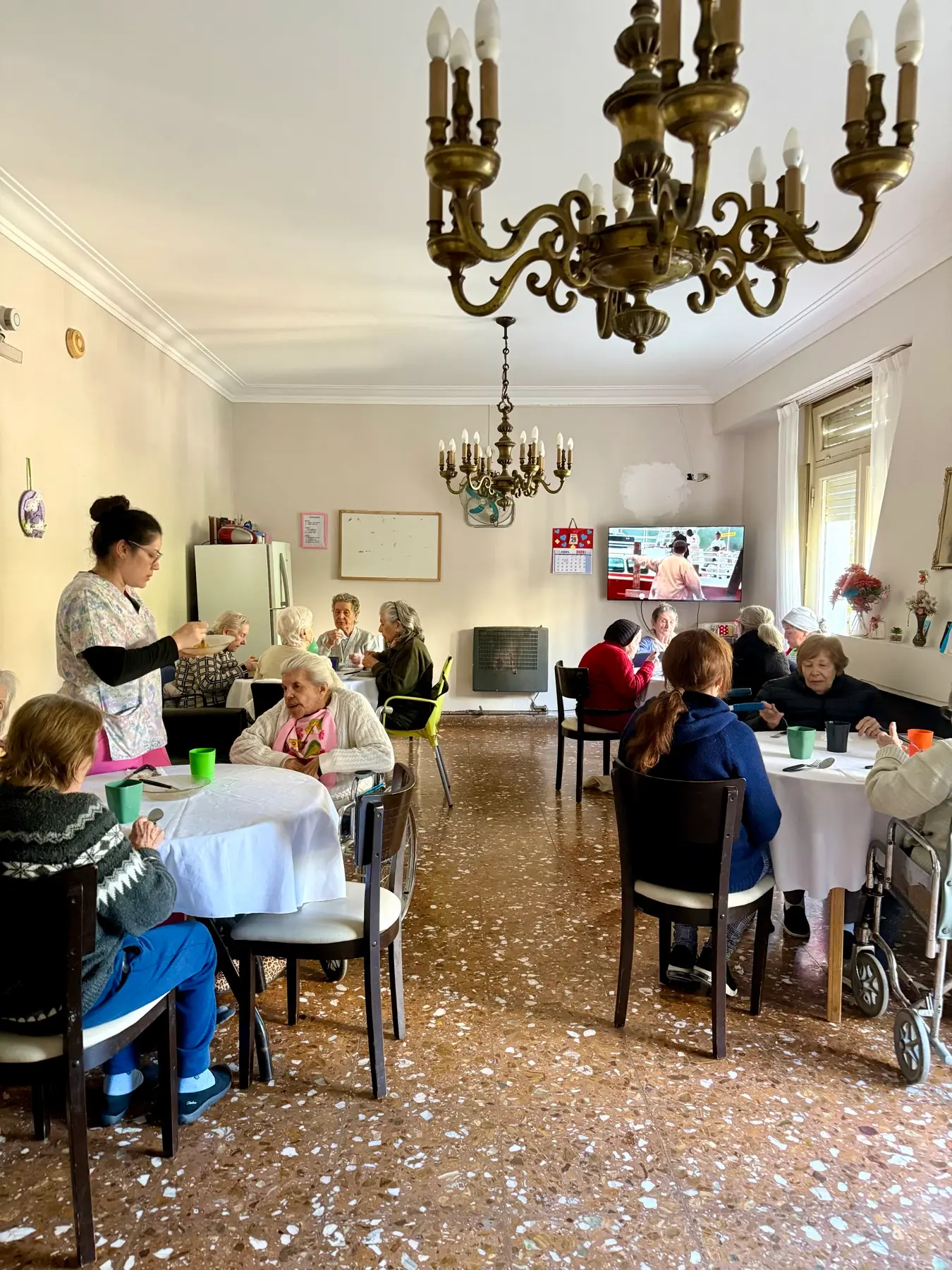 Residentes almorzando en el salón comedor mientras el personal sirve las mesas