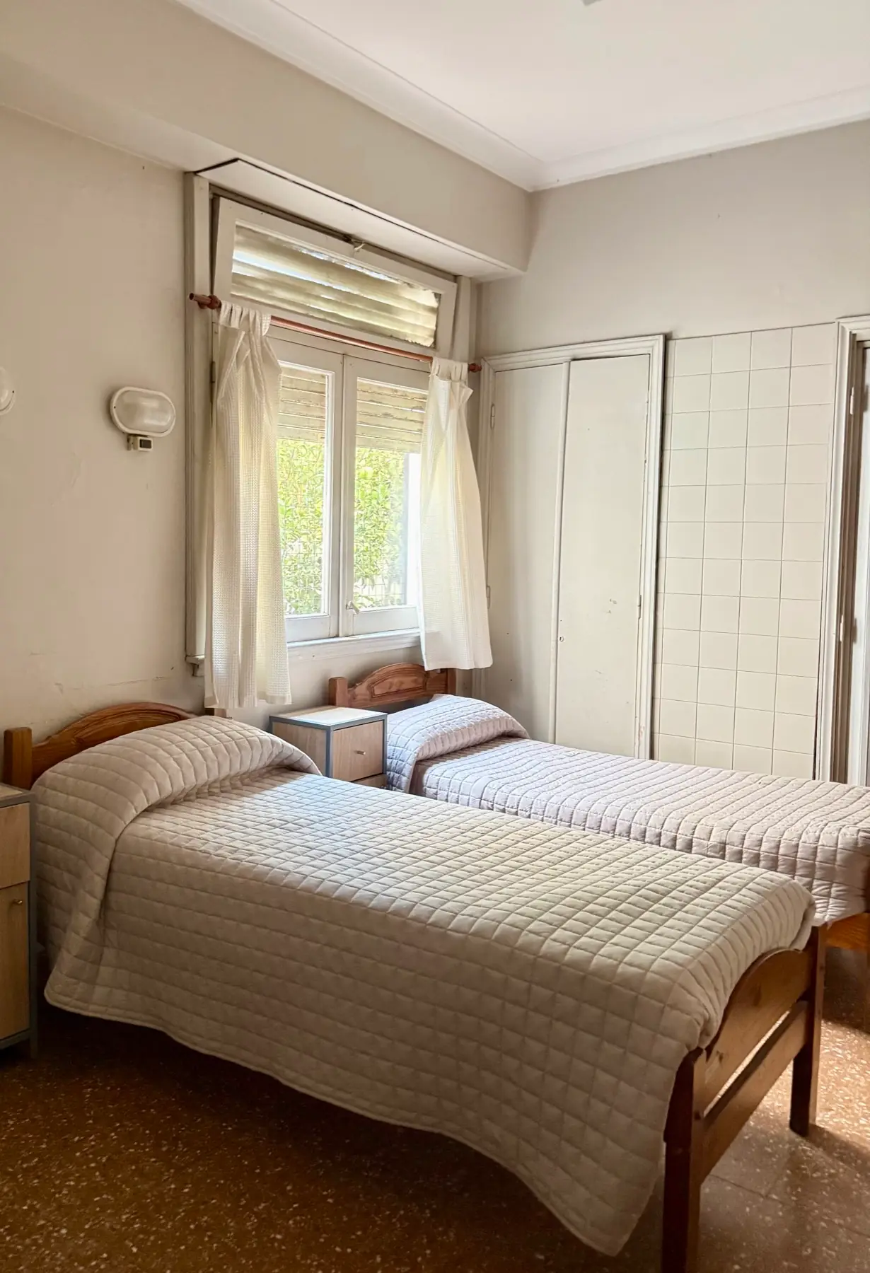 Habitación compartida con dos camas junto a la ventana y placards empotrados