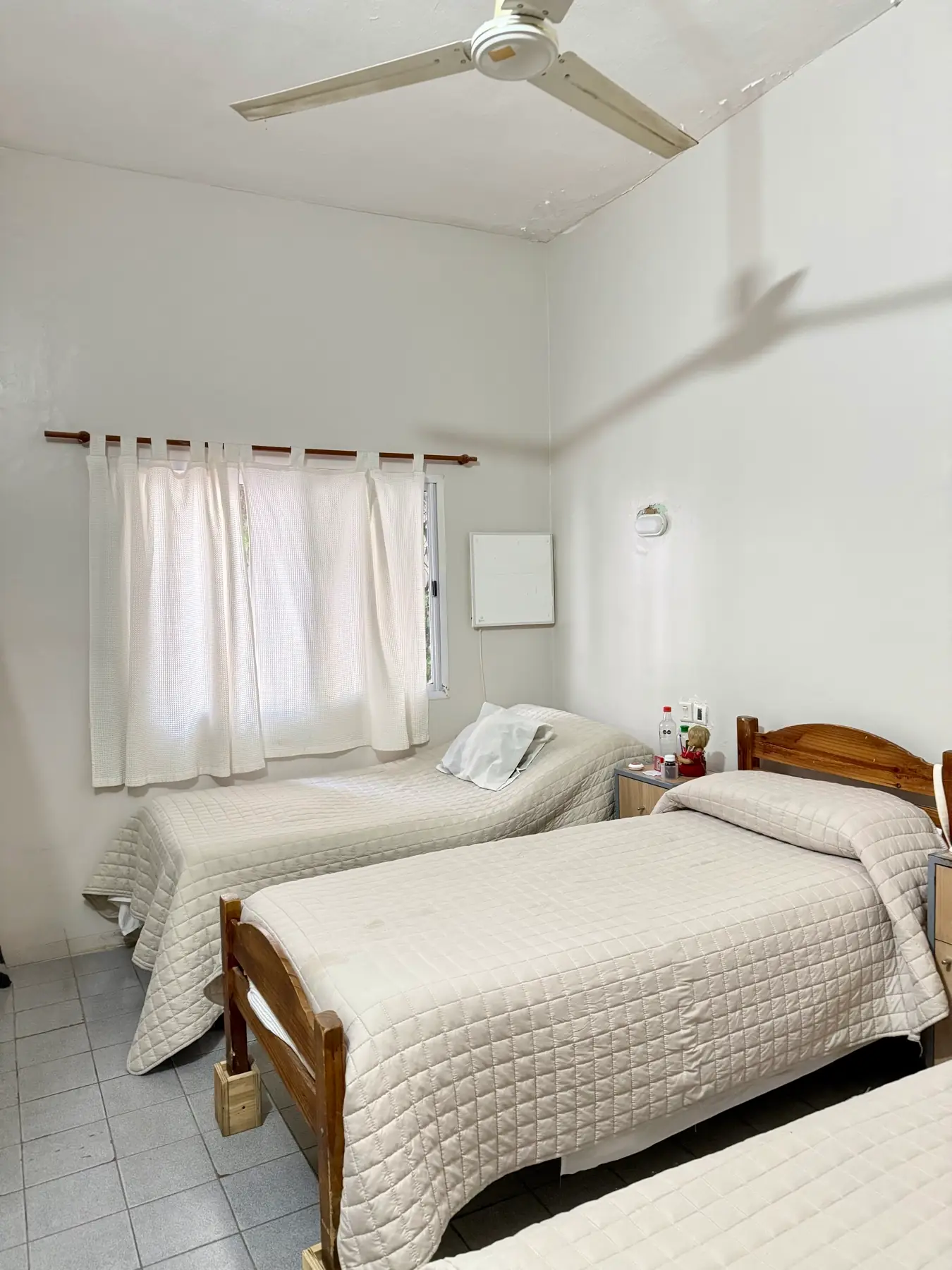 Habitación doble amplia con ventilador de techo y ventana con cortinas claras