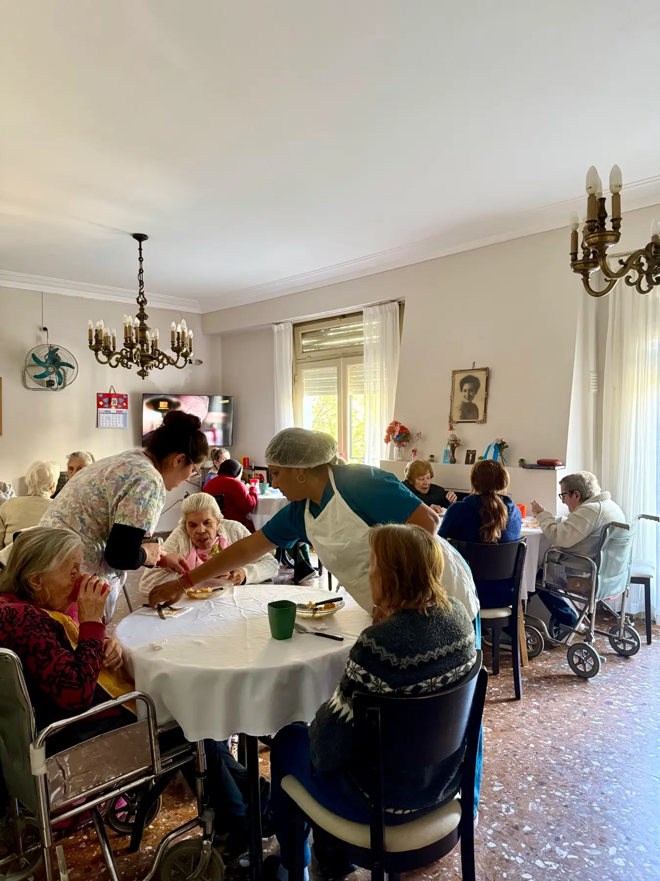 Personal de la residencia acompañando a una residente durante el almuerzo en el salón comedor