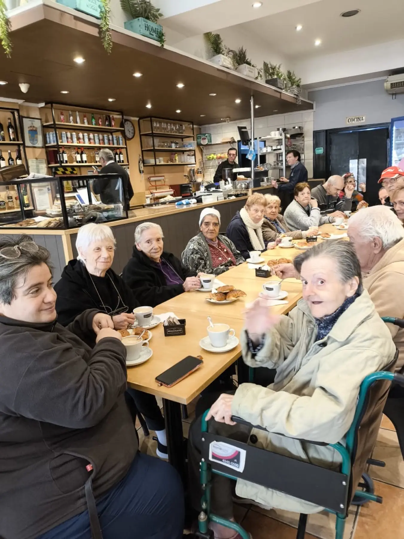 Salida a un café del barrio: residentes compartiendo la merienda en una mesa larga