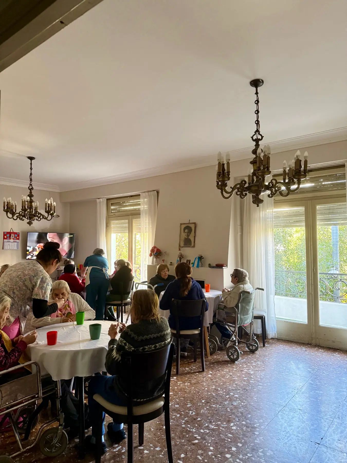 Salón comedor de la residencia con mesas vestidas, arañas de bronce y ventanales al balcón