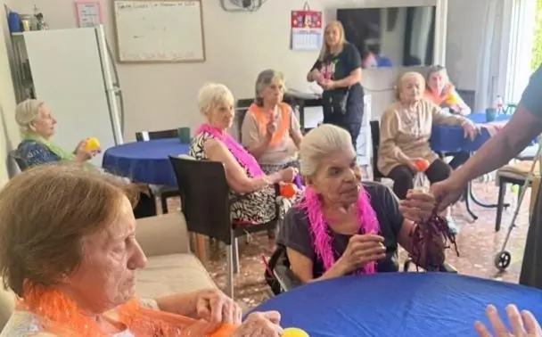 Grupo de residentes reunidas alrededor de una mesa durante el taller de máscaras de carnaval